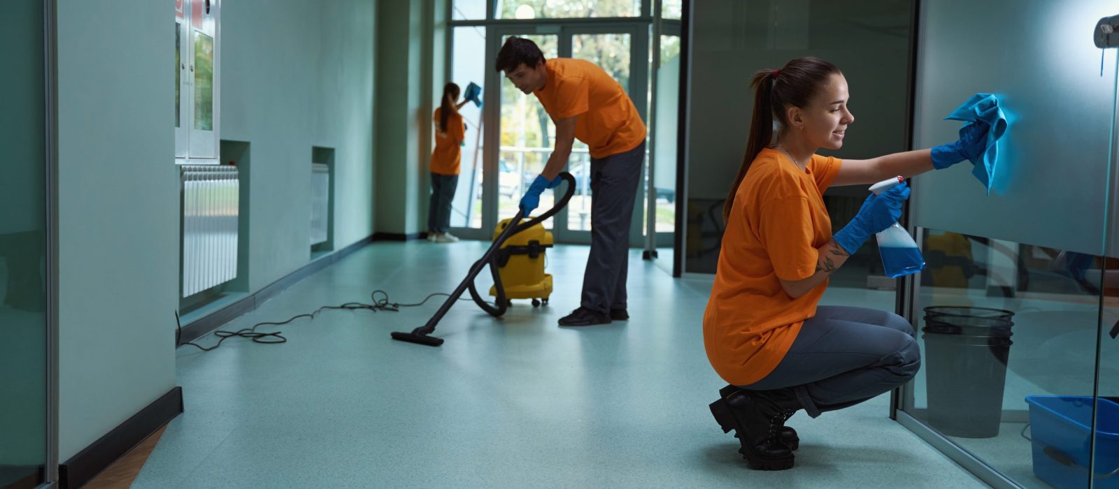 Three energetic cleaners are performing various procedures to make the room clean and cozy